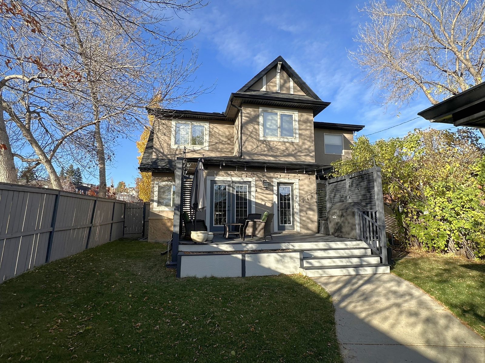 Back of the house with a raised deck, privacy screens and French doors