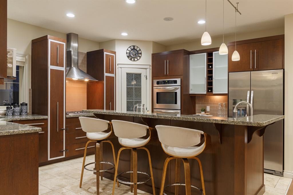 Granite island with breakfast bar, double wall oven and pantry door behind