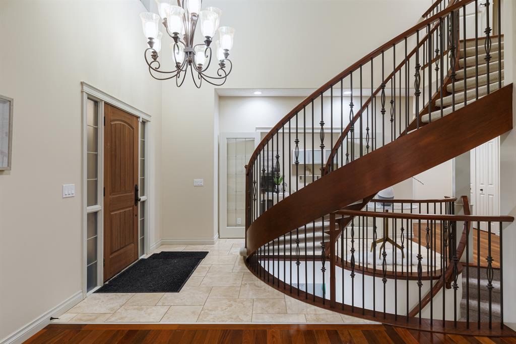 Foyer with a curved staircase, chandelier and wood front door